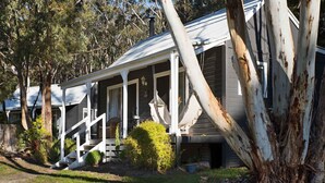 Une rangée de maisons de plain-pied, dotées d’un porche et entourées d’arbres.