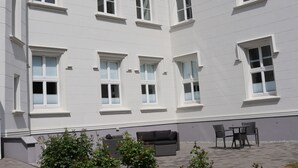 Un edificio con varias ventanas y un patio amoblado al aire libre.