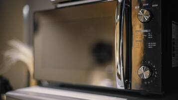 A microwave oven with a digital display and control panel, placed on a white countertop.