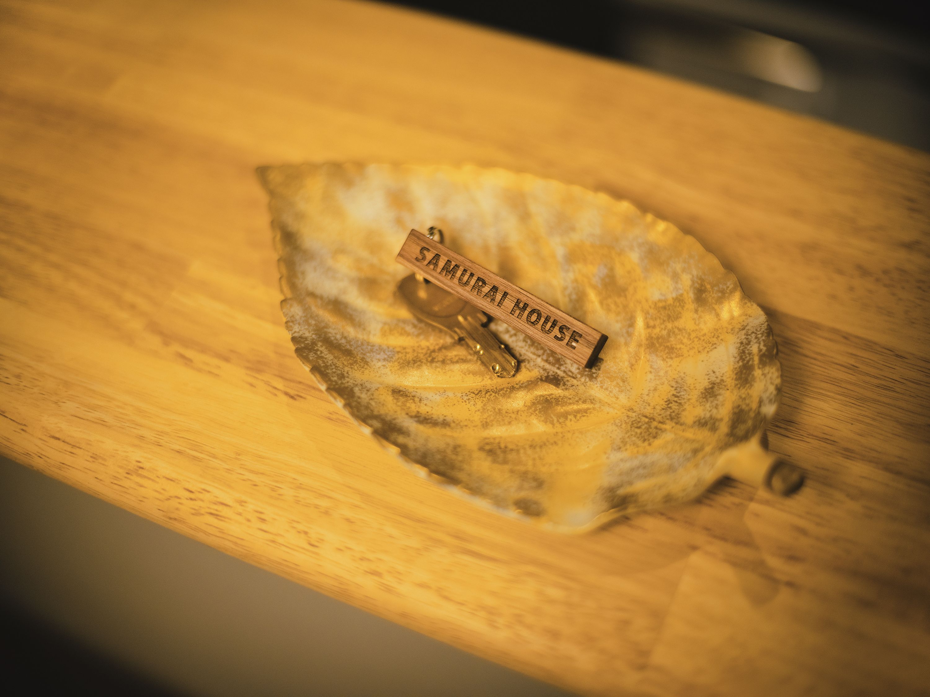 Una mesa de madera con un objeto con forma de hoja y un letrero de madera que dice "SAMURAI HOUSE".