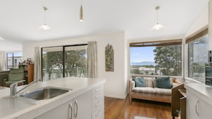 A modern kitchen with a large window, a built-in bench, and a view of the outdoors. - Sweeping Sea Views - Waihi Holiday Home (Waihi Beach)