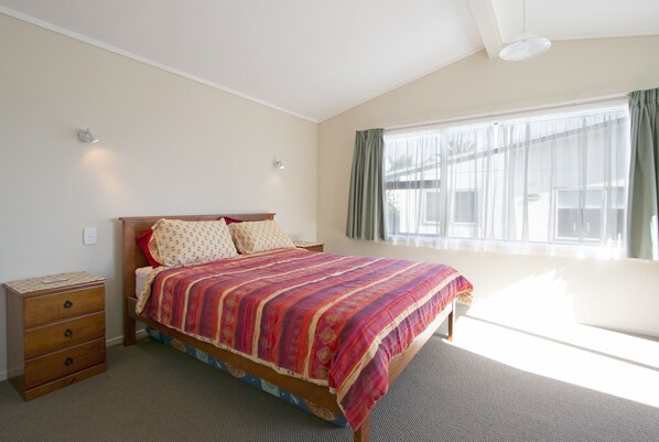 A bedroom with a bed, bedside table, and a window with curtains.