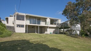 A modern two-story house with a flat roof, large windows, and a balcony. - Sweeping Sea Views - Waihi Holiday Home (Waihi Beach)