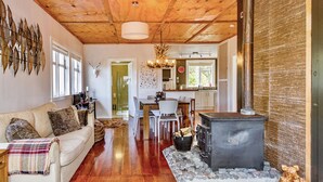 A cozy living room with a fireplace, wooden floors, a sofa, and a dining area.