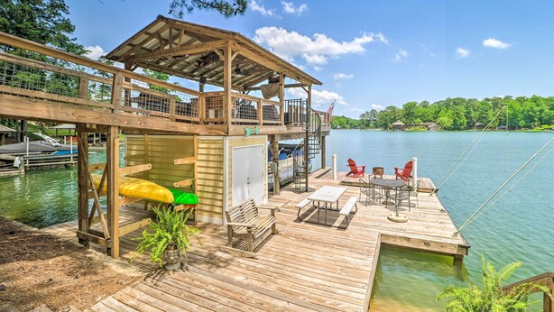 A wooden dock with a covered seating area, a kayak, and a boat docked nearby. - Lake Martin Cabin w/ Luxury Dock & Kayaks! (Eclectic)