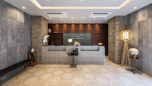 A reception area with a reception desk, a bench, and a decorative shoe sculpture. - Hotel Shinpoin Osaka (Osaka)