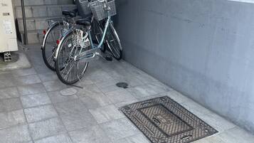 A bicycle parked next to a wall with a metal grate and a manhole cover on the ground.