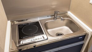 A compact kitchen with a built-in induction cooktop and a stainless steel sink. - Hotel Shinpoin Osaka (Osaka)