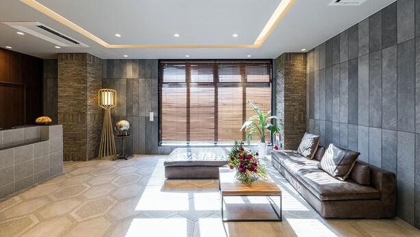 A modern lobby with a reception desk, seating area, and large windows with blinds. - Hotel Shinpoin Osaka (Osaka)