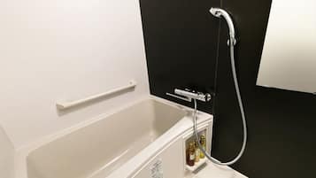 Eine weiße Badewanne mit Duschkopf und Bedienfeld, eine weiße Handtuchstange und ein kleines Ablagebrett mit Toilettenartikeln.