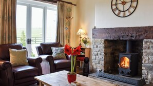 A cozy living room with leather sofas, a wooden coffee table, a stone fireplace, and a large wall clock. - High Dalton Hall Cottage (Newsham, near Richmond)