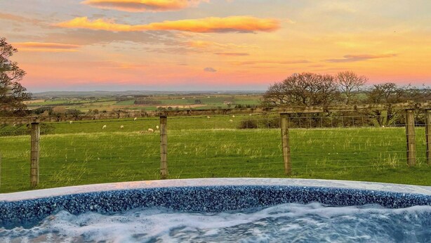 A hot tub with a view of a grassy field and trees during sunset. - High Dalton Hall Cottage (Newsham, near Richmond)
