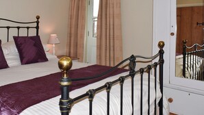A neatly made bed with a headboard, a bedside lamp, and a mirror on the wall. - High Dalton Hall Cottage (Newsham, near Richmond)