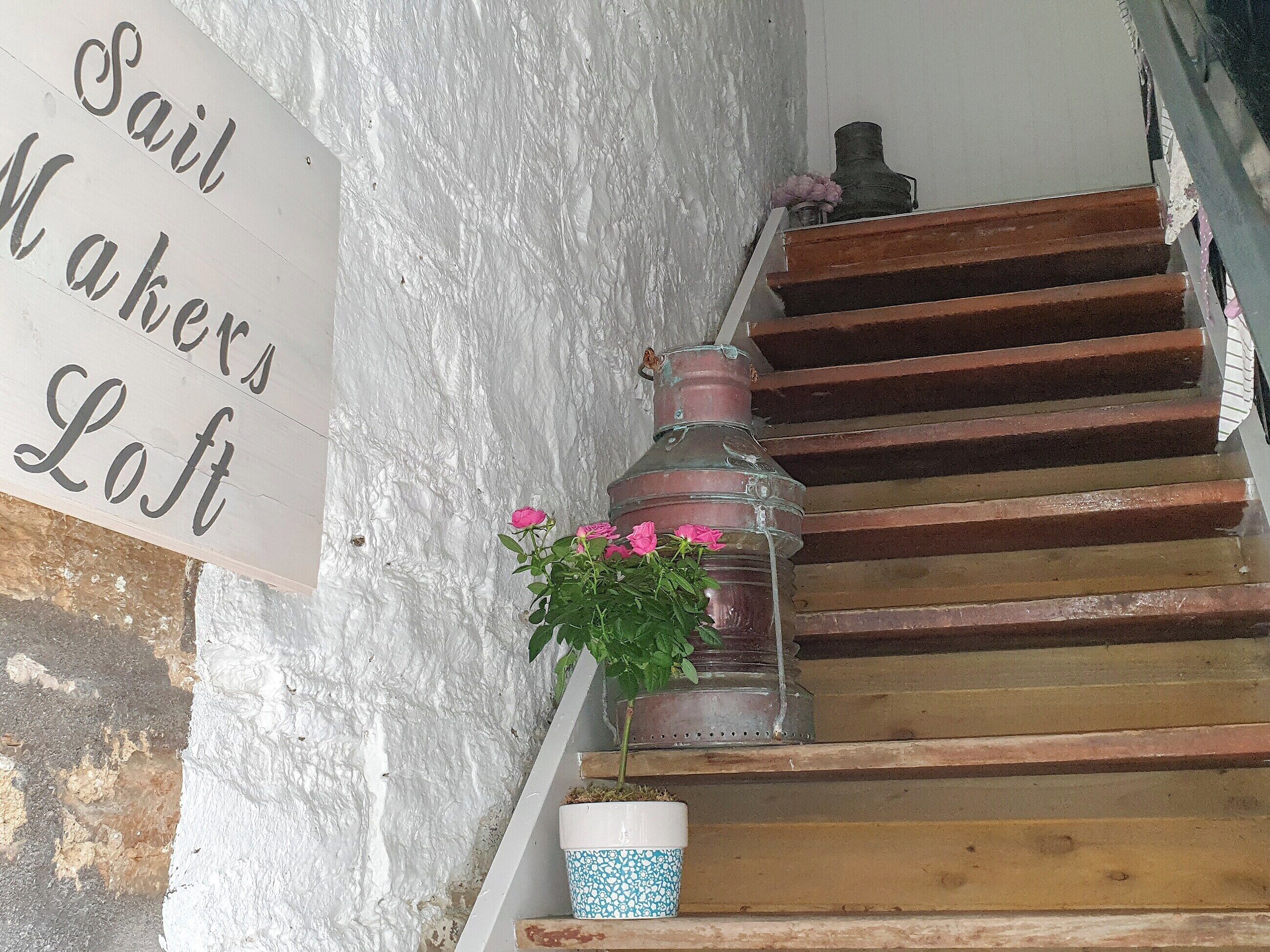 Een trap met een bordje waarop staat 'Sail Makers Loft'.