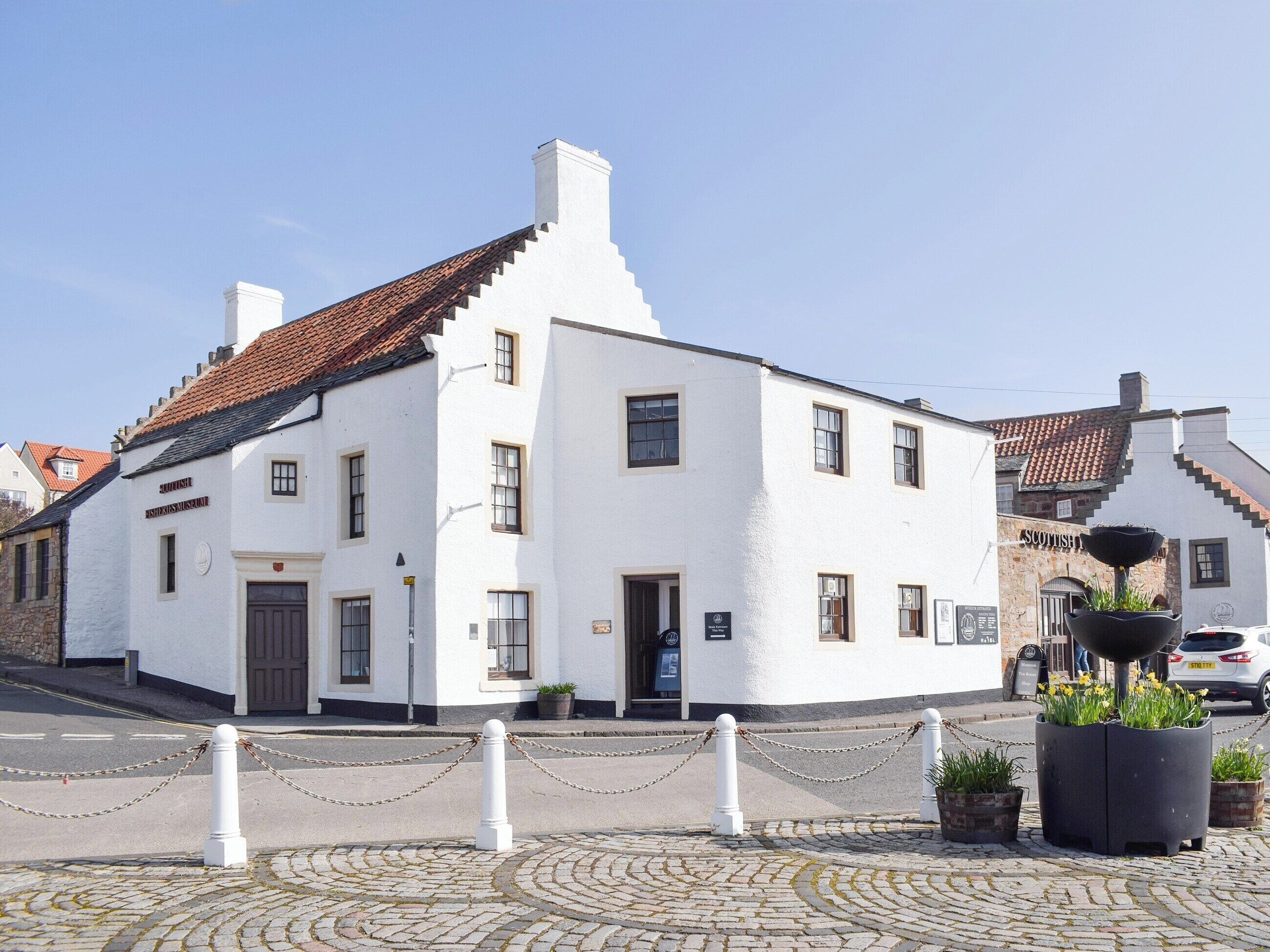 Un bâtiment blanc à l’architecture traditionnelle, doté d’une façade en pierre et d’un toit recouvert de tuiles.
