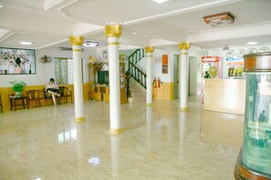 A spacious lobby with marble flooring, white columns with gold accents, a staircase, and a Coca-Cola refrigerator. - Khach San Thu Nga (Hanoi)