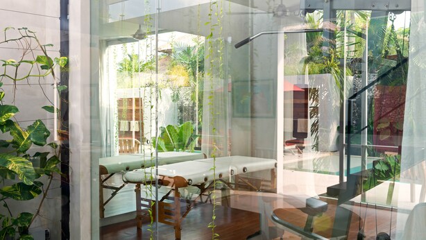 A modern spa room with a glass partition, wooden flooring, and a bench. - Villa Alina (Seminyak)