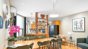 A modern kitchen with wooden cabinets, a black refrigerator, and a dining area with a wooden table and green chairs. - Accueil CHEZ Francois (Montreal)