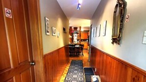 A hallway with wooden paneling, a patterned carpet, and a dining area in the background. - Accueil CHEZ Francois (Montreal)