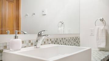 A bathroom with a white sink, chrome faucet, and a mirror above it.