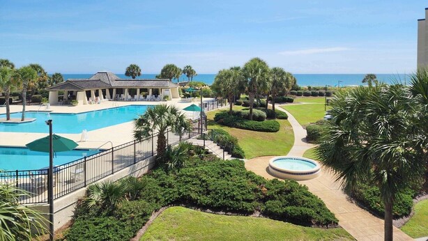 Et resort med swimmingpool, overdækket loungeområde og havudsigt.