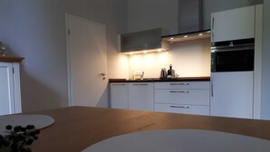 A modern kitchen with white cabinets, a wooden countertop, and built-in appliances.