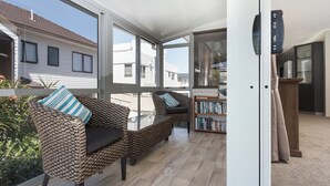 Una sala moderna con un conjunto de sofá, una estantería y vistas a casas vecinas a través de amplios ventanales.