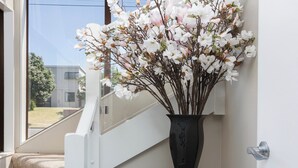 Una escalera con un jarrón de flores blancas sobre un pedestal.