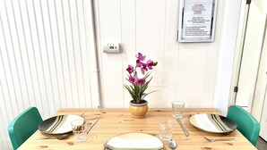 A dining table set with plates, cutlery, and a vase with flowers. - Cozy Apartment unit is Available to Rent (Long Beach)