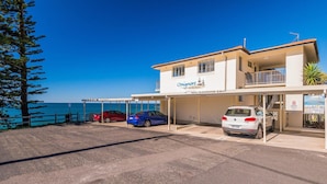 A building with a sign reading "Craigmore on the Beach" and a parking area with several cars. - Craigmore On the Beach Unit 13 - One of the most desirable holiday locations in Yamba. (Yamba)