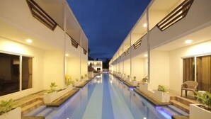 A hotel corridor with a long, narrow pool, white walls, and potted plants along the sides. - The Story Resort Bohol (Panglao)