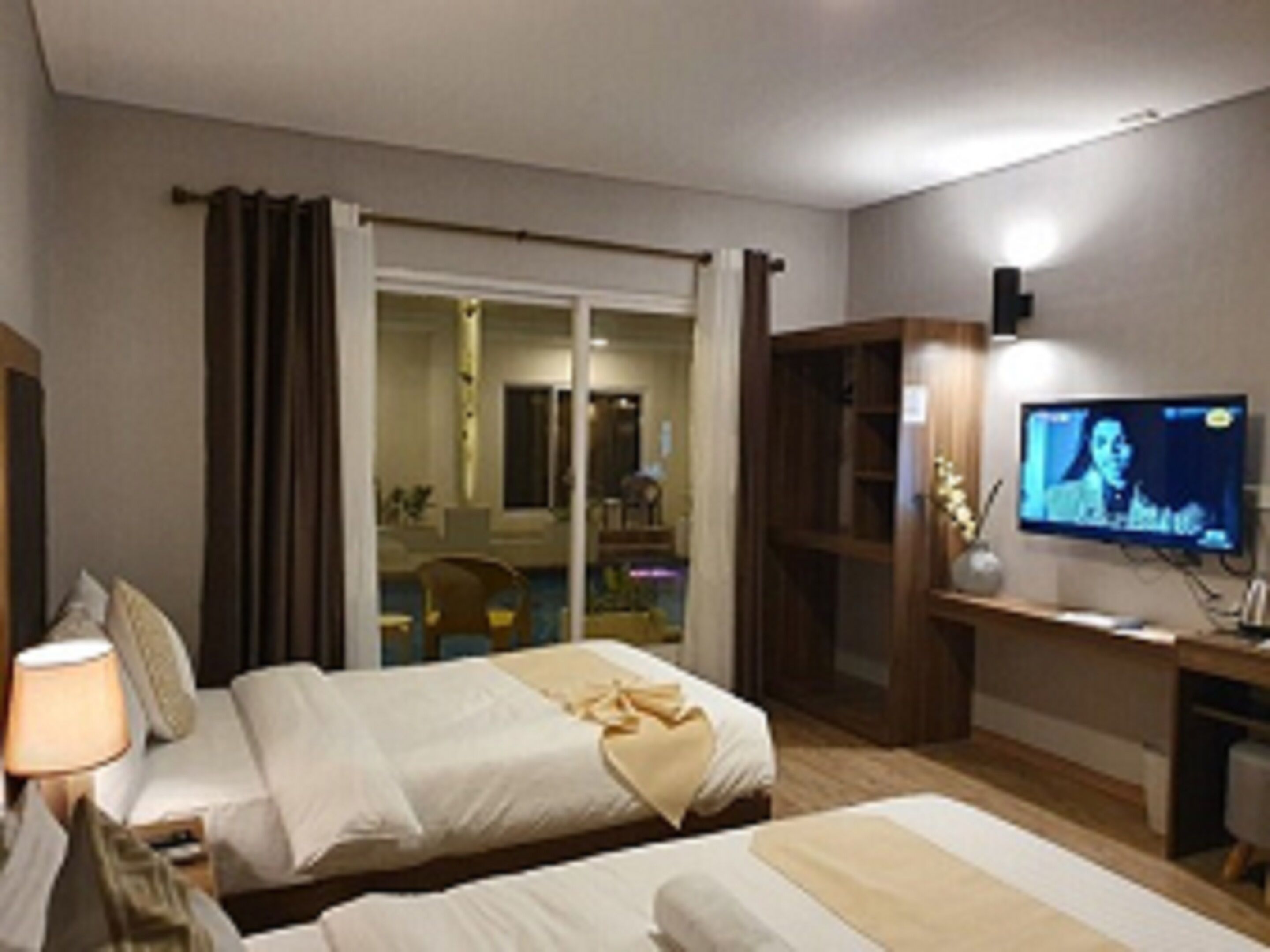 A hotel room with two beds, a television, and a desk.
