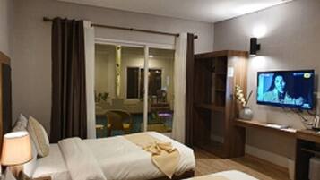 A hotel room with two beds, a television, and a desk.