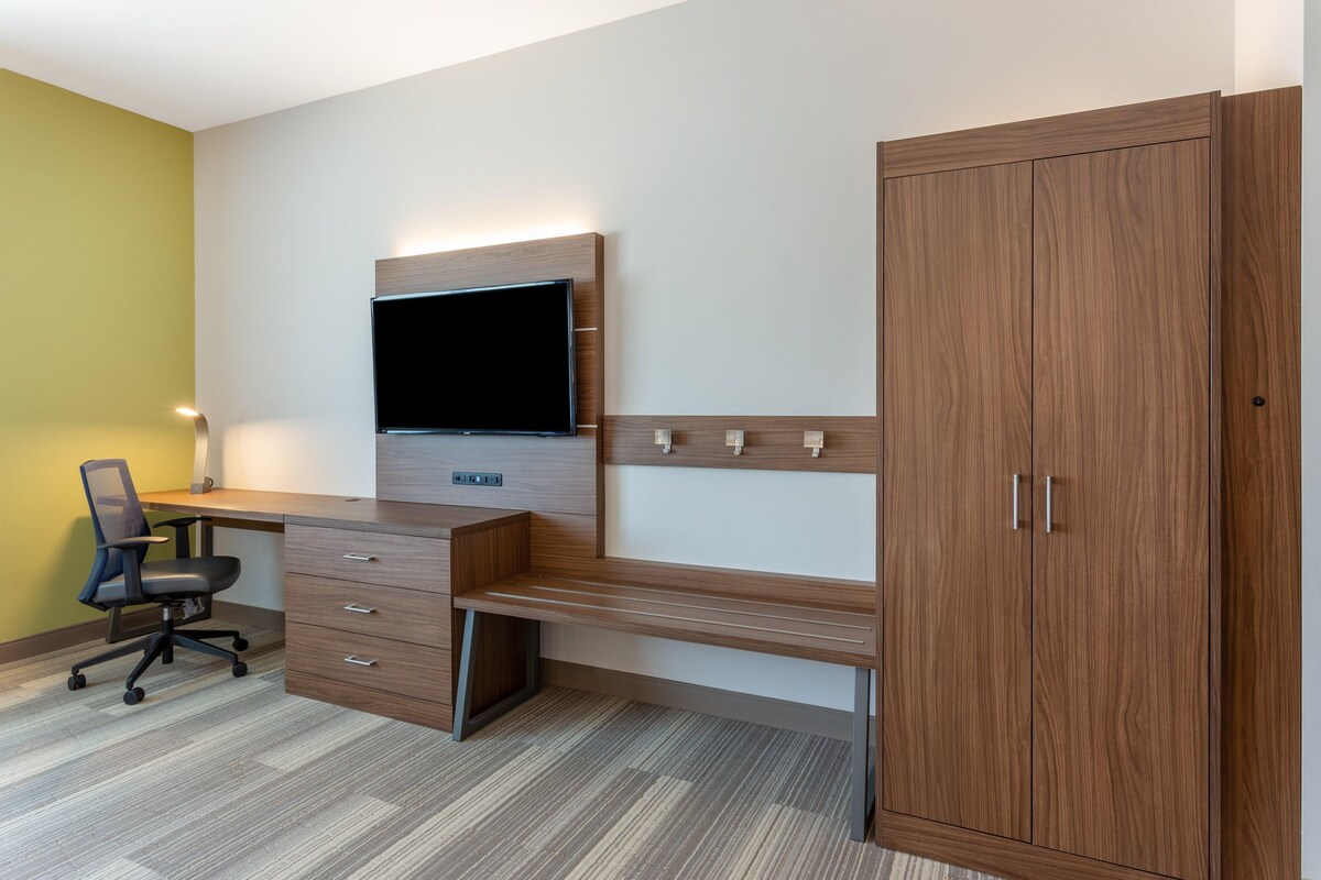Ein moderner Arbeitsraum mit einem Holztisch, einem Wandfernseher und einem großen Schrank.