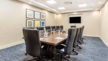 A conference room with a long table, black chairs, and framed artwork on the wall.