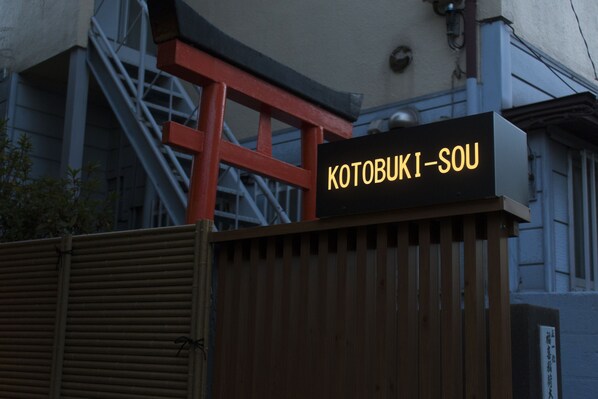 Un letrero con el texto "KOTOBUKI-SOU" sobre un fondo negro.