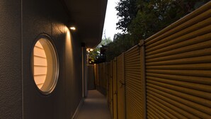 A corridor with a circular window, a wooden fence, and a closed shutter door. - Kotobuki Sou (Tokyo)