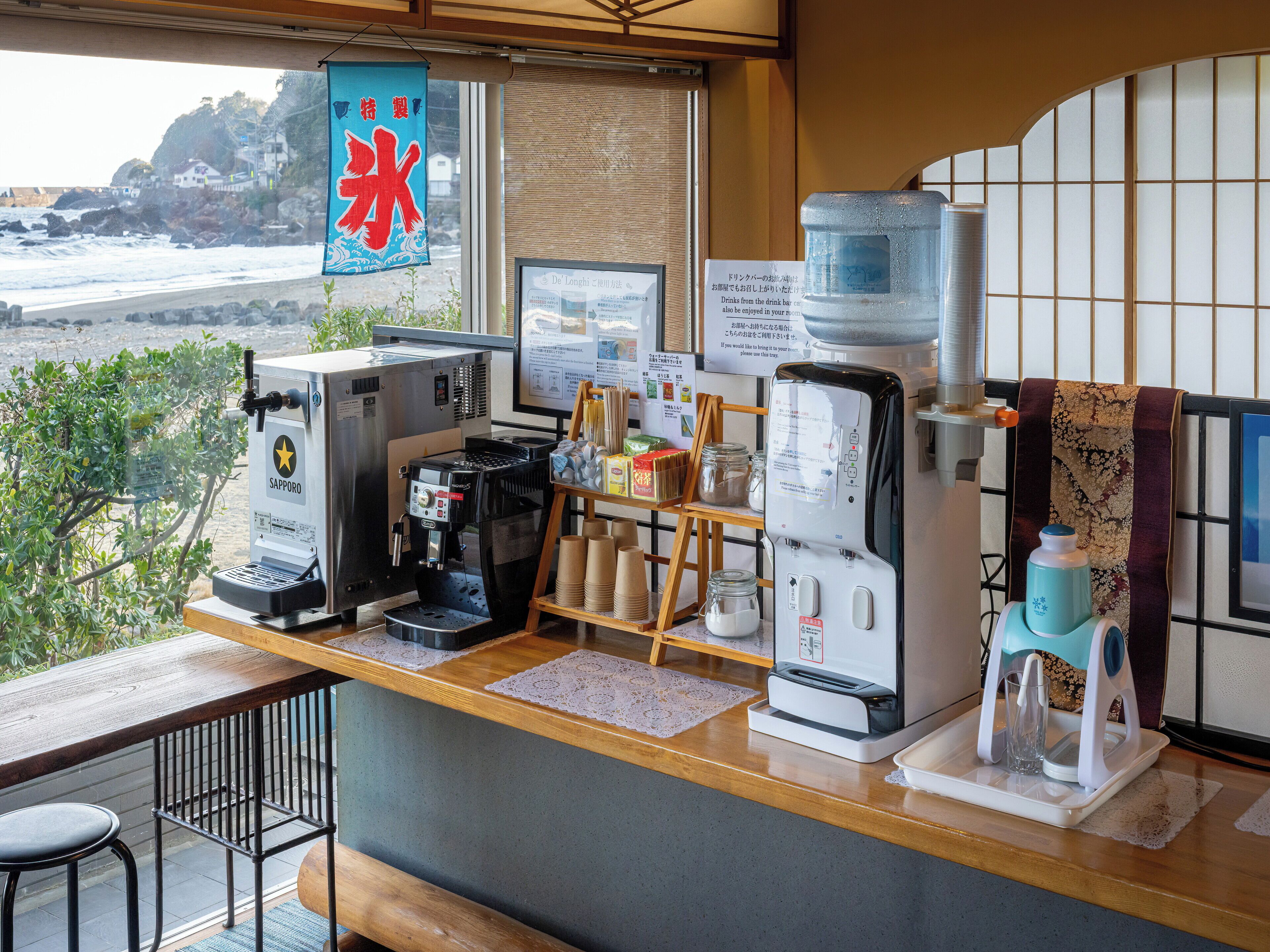 Un mostrador de cafetería con una máquina de café, un dispensador de agua y una pizarra de menú.