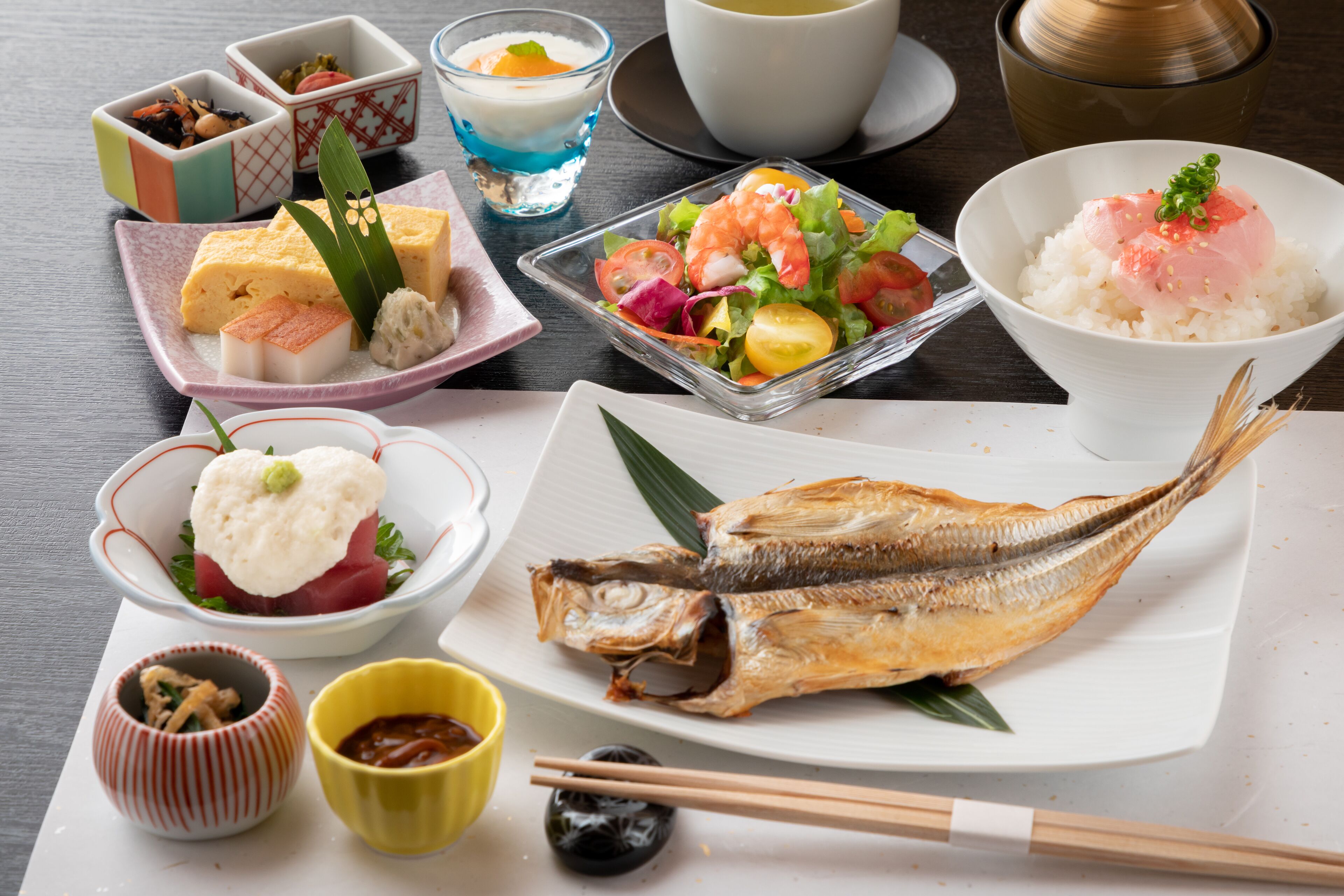 A variety of Japanese dishes including sashimi, rice bowls, and a whole fish on a plate.