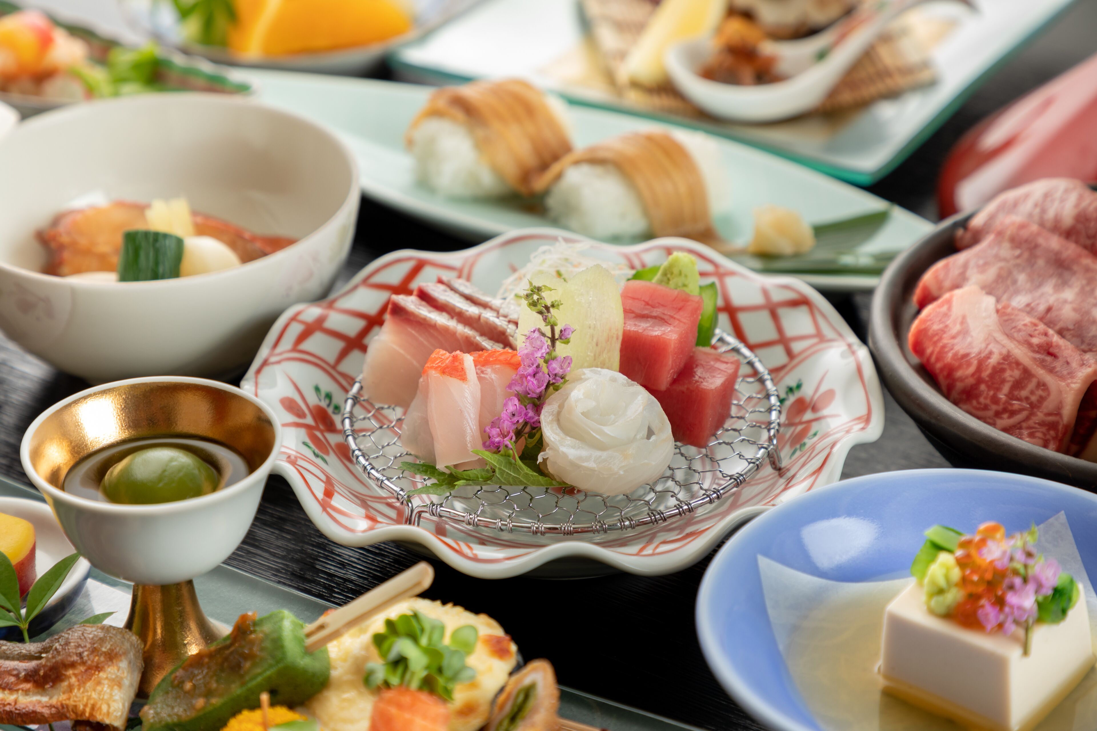 A variety of Japanese dishes on a table, including sushi, sashimi, and other appetizers.