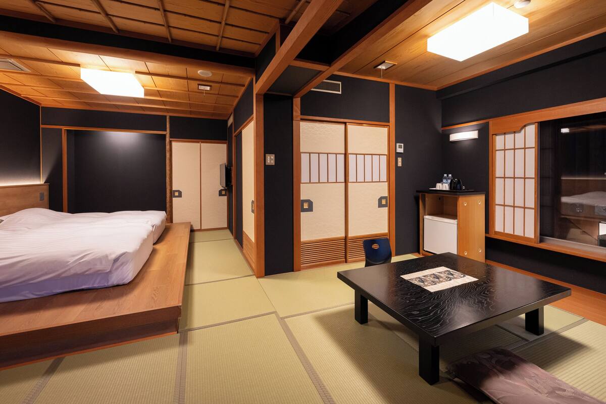 A traditional Japanese room with tatami flooring, a bed, a table, and sliding doors.
