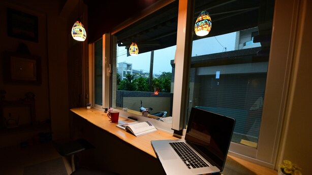 Un espace de travail avec un ordinateur portable, une tasse rouge et un carnet sur un bureau en bois.