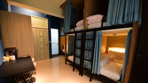 Une chambre de type dortoir, avec des lits superposés, un bureau et une chaise.