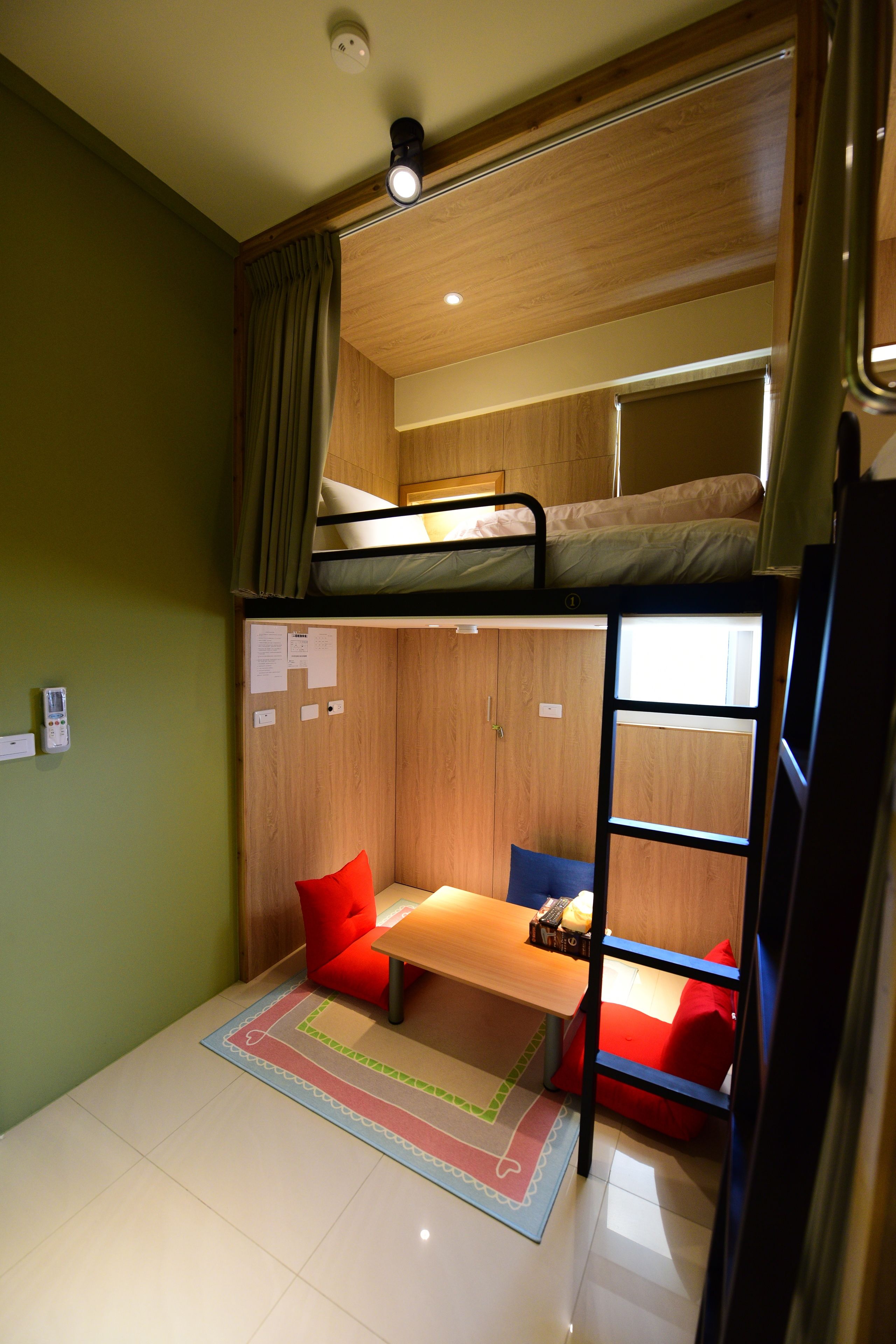 A compact room with bunk beds, a small desk, and a red chair.