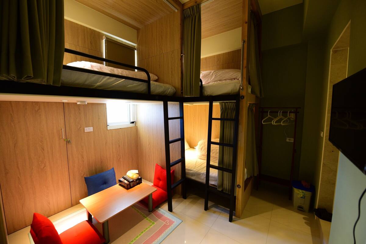 A compact room with bunk beds, a small desk, and a chair.