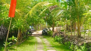 A garden pathway with stepping stones, surrounded by lush greenery and palm trees. - Gading Treehouse (Penida Island)