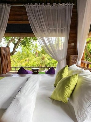 A bed with white linens and green pillows, a wooden ceiling, and a view of greenery outside. - Gading Treehouse (Penida Island)