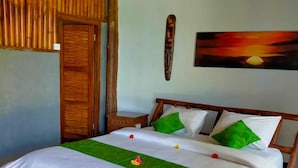 A bed with white bedding and green accents, a wooden headboard, a wooden door, and a sunset painting on the wall. - Gading Treehouse (Penida Island)