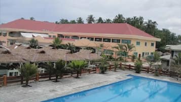 Un hotel con piscina, palmeras y un edificio de techo rojo.