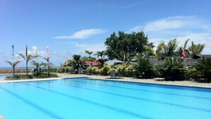 A clear blue swimming pool with a tiled edge, surrounded by palm trees and a wooden deck. - Villa Maria Luisa Hotel (Tandag)